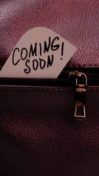 Text Coming Soon on paper. Close up of zip on dark textured leather. Grunge style	