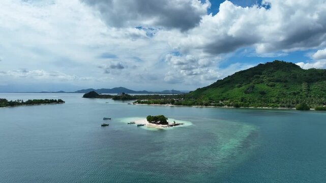 Full island view with outriggers moored, conical Lombok hill centred behind - 4k aerial