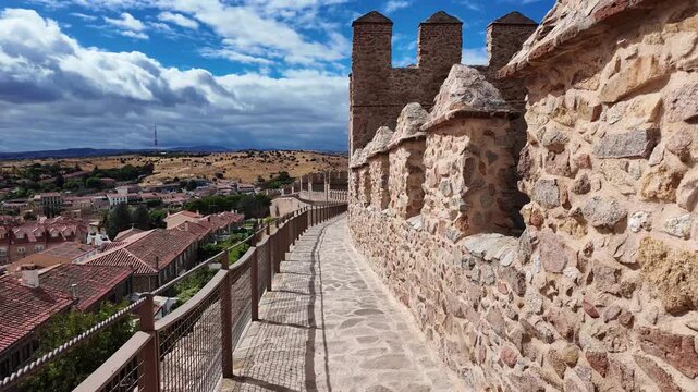 View along the famous medieval city walls of &Aacute;vila, Spain. A stone pathway runs beside historic battlements overlooking the old town, showcasing one of Europe&rsquo;s best-preserved fortifications.