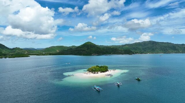 Traditional outrigger boats anchor around a sandbar island, green hills backdrop, Lombok