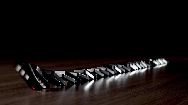 Black dominoes falling in a chain reaction, cause and reason connection, crisis idea economy business, metaphor for chain reaction, business strategy and risk management, butterfly effect