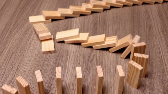 Wooden dominoes falling in a chain reaction, cause and reason connection, crisis idea economy business, metaphor for chain reaction, systemic change, the power of a single action, butterfly effect