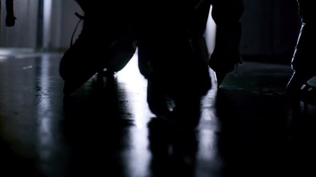 Hockey players leave locker room walking through dedicated corridor leading directly toward ice arena. Transition moment builds anticipation