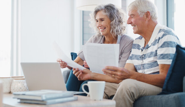 Laptop, document and old couple in house with smile, life insurance website or retirement planning. Married, senior people and reading paperwork on sofa with computer, estate policy and pension fund.