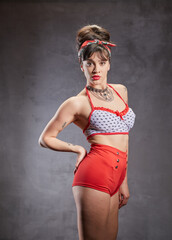 Obraz premium A woman with a fit figure and stylish clothes is posing in a studio. She is wearing red shorts and a polka-dot top.
