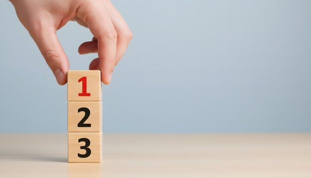 A human hand carefully places the number one wooden block on top of a stack of numbered blocks creating a clear sequence on a light table
