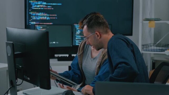 software engineer and programmer collaborating on software development on multiple monitors at night office,developer write prompt AI bot IT app program,coding ai agent,data analytics in tech office.