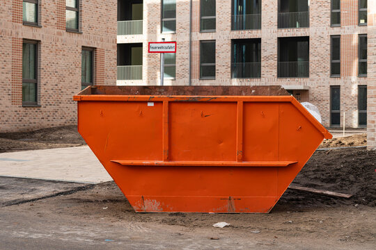 Orange dumpster on construction site near new buildings