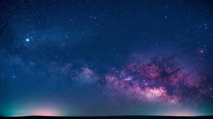 Fototapeta premium Breathtaking photograph of the Milky Way galaxy arcing over a dark horizon with a distant city glow.