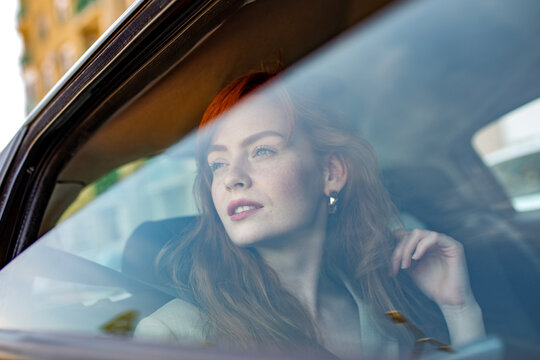 Smiling woman in taxi back seat talking on smartphone. Ride sharing service, passenger using mobile app, luxury car rental, chauffeur transport, business travel, urban mobility and lifestyle concept.