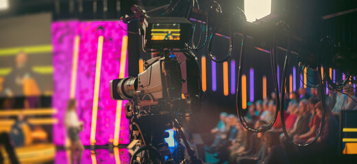 Professional broadcast camera in modern TV studio with neon lights and copy space