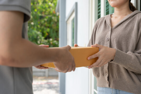 Happy smiling woman receives boxes parcel from courier in front house. Delivery man send deliver express. online shopping, paper containers, takeaway, postman, delivery service, packages