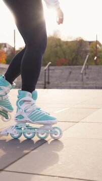 A low-angle vertical shot of a rollerblader practicing their inline skating routine on a paved park path. Captures an active lifestyle and the aesthetic of urban skating during a sunny day.