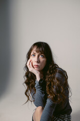 Naklejka premium Portrait of a young woman with long wavy hair and blue eyes on a cyclorama. Feminine photo shoot