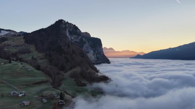 Alpine cliff and village above cloud inversion near Walensee Switzerland