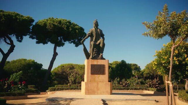 Bronze statue on pedestal surrounded by manicured gardens