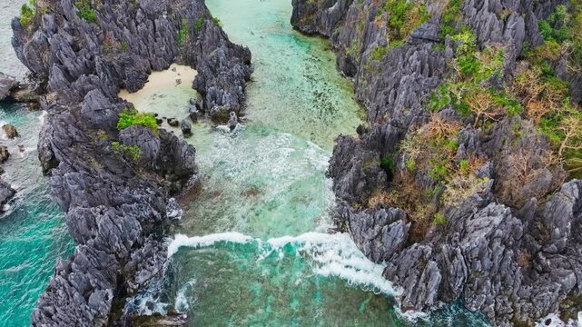 Tourists appear as tiny figures on Hidden Beach lagoon Matinloc island