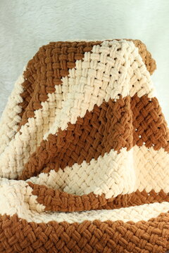 Handmade beige and brown puffy blanket with large loops on furry white blanket.