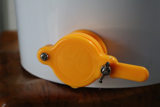 Close up of a honey gate also known as a honey tap or honey valve on a white bucket