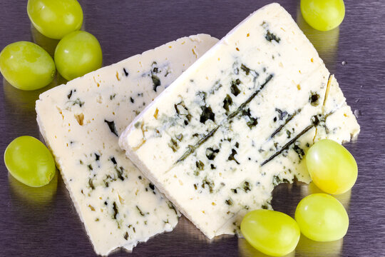 Slices of blue cheese with yellow grapes close-up