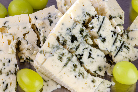Pieces of blue cheese with yellow grapes close-up