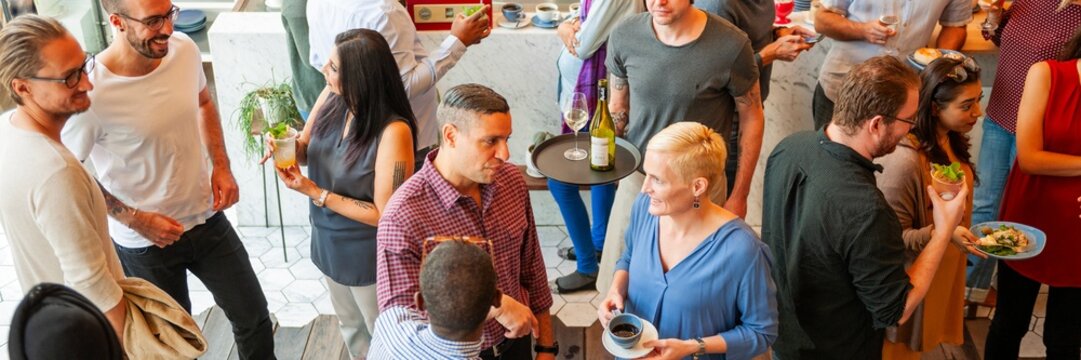 Diverse group socializing at a casual gathering. Men and women, various ethnicities, chatting and enjoying drinks. Lively atmosphere with people mingling. Diverse people mingle at social gathering.