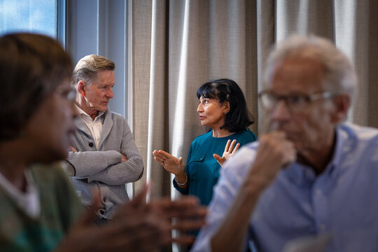 Female business expert discussing with male colleague while standing near curtain of window in office