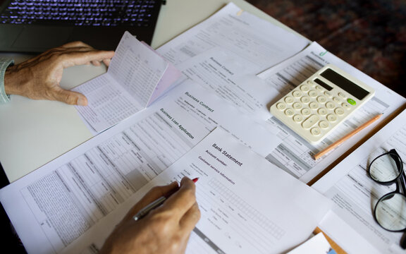 close up shot, businessman checking bank statement and balance in passbook review all relevant documents for start new business online, E-commerce