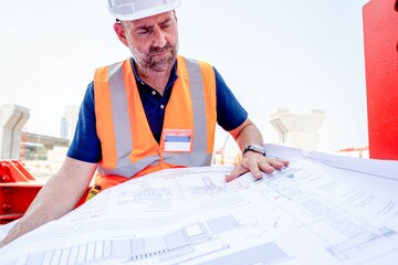 Engineer reviewing construction plans outdoors.