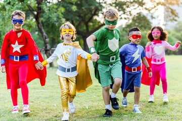 Children dressed as superheroes outdoors.