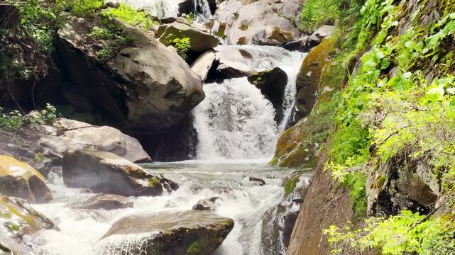 4K shot of a scenic waterfall flowing in the middle of the mountain valley  as seen near Tindi village in Lahaul and Spiti district, Himachal Pradesh, India. Scenic view of waterfall in the mountain.