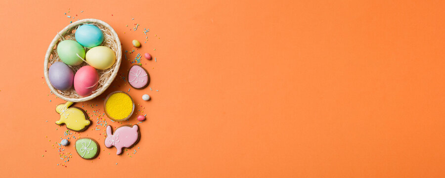 Colorful easter cookies in basket with Multi colors Easter eggs on colored background . Pastel color Easter eggs. holiday concept with copy space