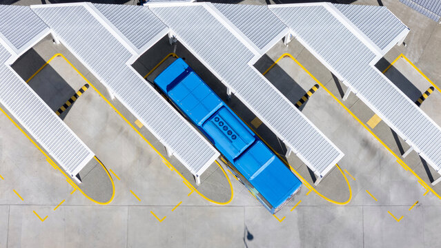 Aerial view of a bright blue bus nestled under a geometric canopy of white shelters with yellow outlines, Halifax Street, Nelson, Nelson Region, New Zealand.