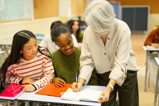 Teacher helping high school students during lesson in class