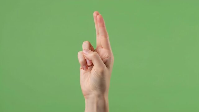 Close-up of a hand forming the number 2 with fingers against a green background.