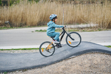 Naklejka premium Child cycling up a roller on outdoor pump track