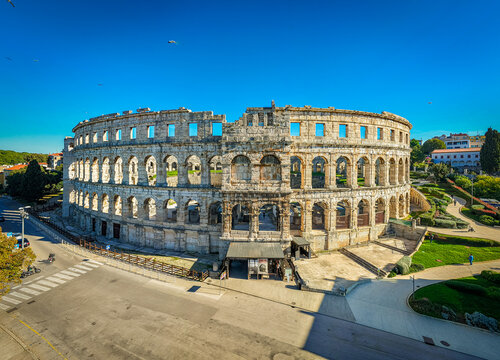 Aerial view of the ancient Roman amphitheater, its weathered stones standing against the clear blue sky, a testament to history, Pula, Istria County, Croatia.