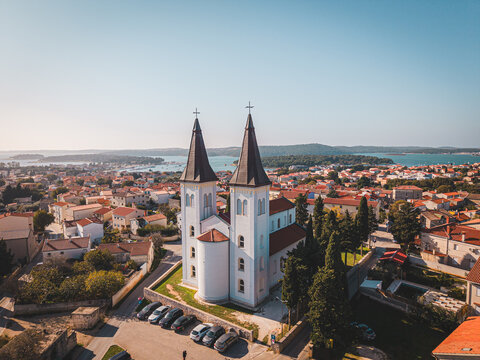 Aerial view of the striking white facade of the Church of Our Lady of the Sea sharply contrasts against the terracotta rooftops, Medulin, Istria County, Croatia.