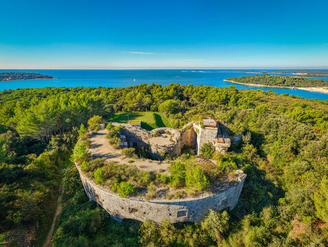 Aerial view of Fortress Bourguignon embraced by lush green forests, with the Adriatic Sea shimmering in the distance, Pula, Istria County, Croatia.