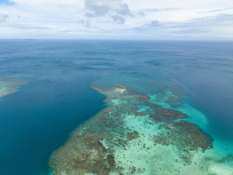 Aerial view of the vibrant turquoise waters embracing the Camar Rock Island reef, a jewel amidst the vast ocean, Jepara Regency, Central Java, Indonesia.