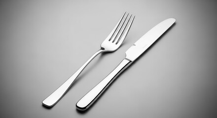 A silver fork and knife are placed on a gray surface in a minimalist setting.
