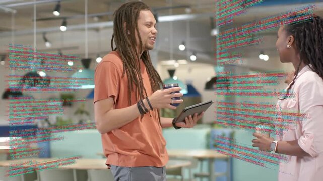 Smiling coworkers in casual dress talking work in lounge, code overlay rising as man tilting tablet