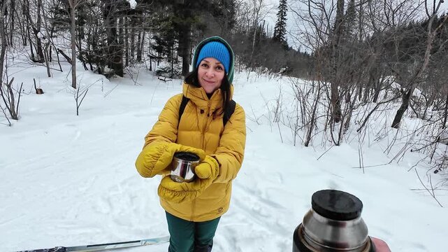 Woman In Winter Scene Pours Hot Drink. Cold Outdoor Setting With Woman Sharing Warm Coffee Moment. Woman In Snowy Landscape Pours Steaming Coffee From Thermos During Winter Daylight