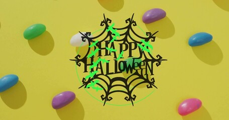Obraz premium Showing central black spiderweb saying HAPPY HALLOWEEN on yellow table with neon bats, jellybeans