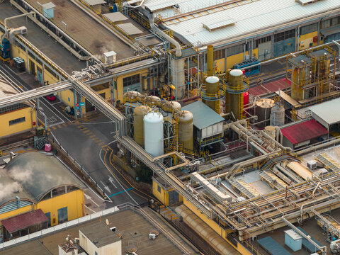 Aerial view of industrial buildings linked by pipes, creating a network of metallic structures against the backdrop of Settecamini, Lazio, Italy.