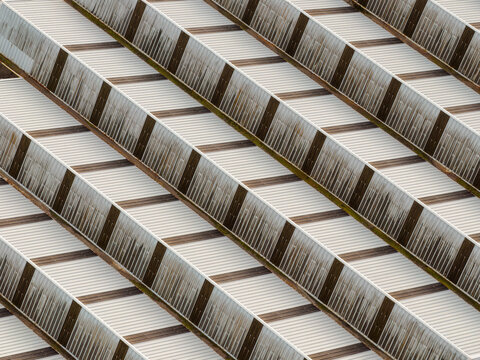 Aerial view of rhythmic patterns of light and shadow dance across the corrugated rooftops, creating a mesmerizing geometric tapestry, Settecamini, Lazio, Italy.