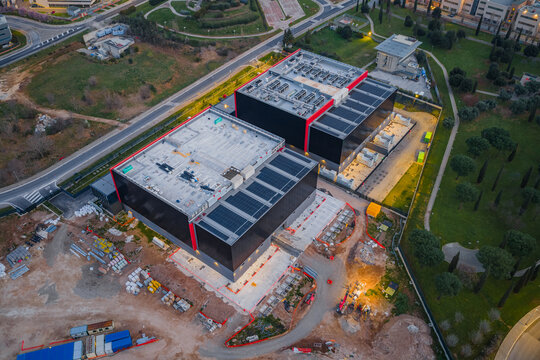 Aerial view of modern data centers with solar panels contrasting against the surrounding landscape, the scene bathed in the warm glow of the setting sun, Settecamini, Lazio, Italy.