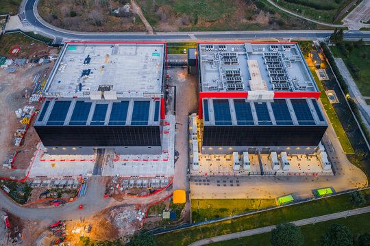 Aerial view of the imposing data center complex, its angular forms sharply defined against the surrounding greenery, a modern fortress of technology, Settecamini, Lazio, Italy.