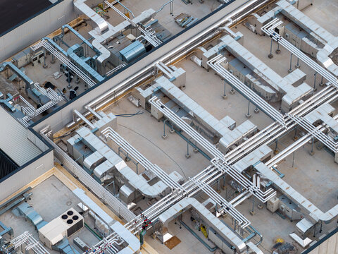 Aerial view of a complex network of pipes and ventilation systems sprawls across a building rooftop, creating an intricate industrial landscape, Settecamini, Lazio, Italy.