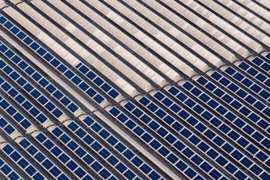 Aerial view of a geometric expanse of solar panels casting shadows in stark contrast to the light, Settecamini, Lazio, Italy.